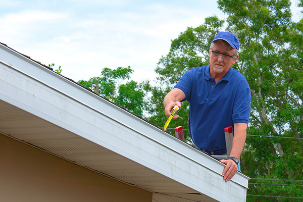 A roofer inspecting a residential roof for damage.